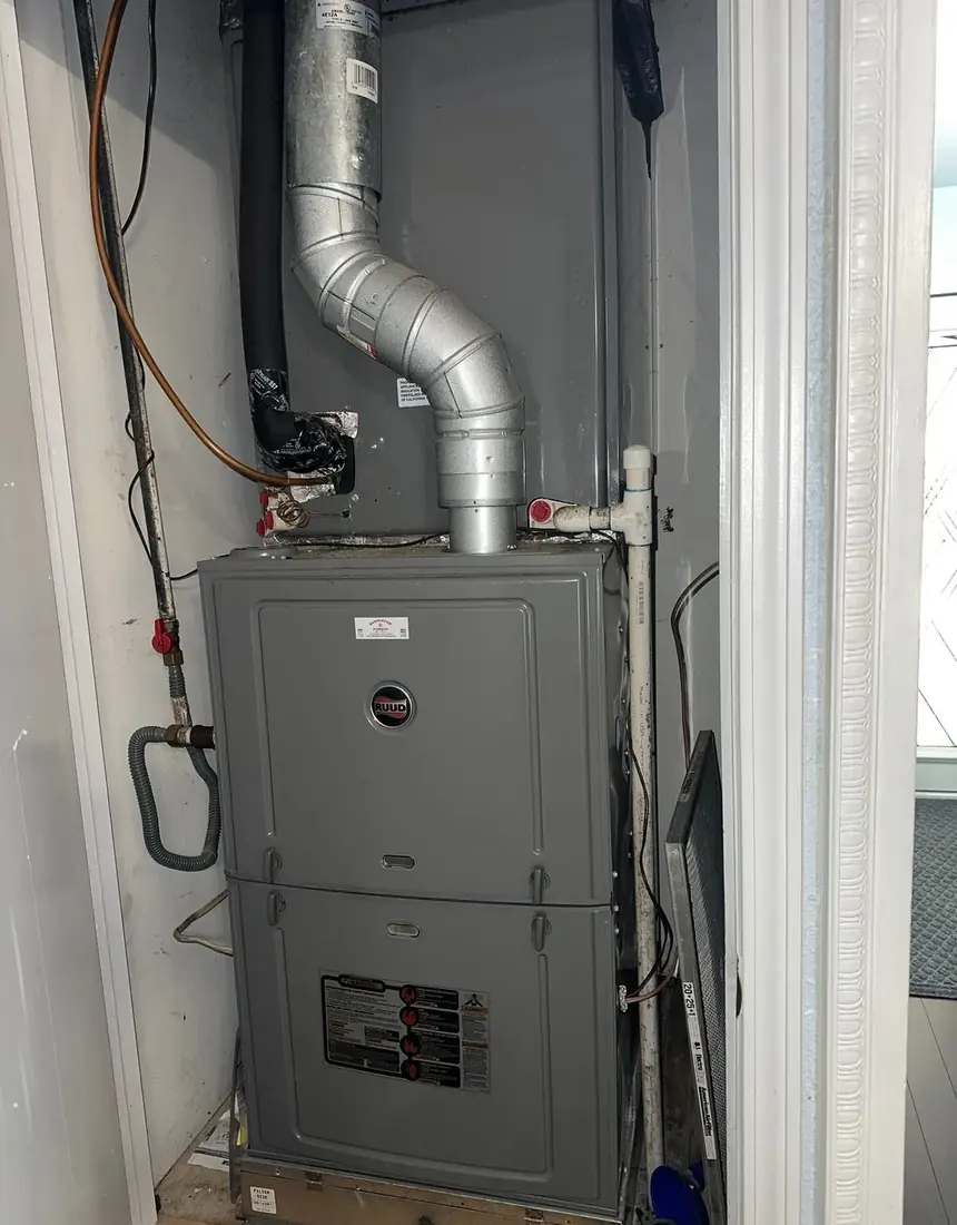 A gas furnace installed in an interior closet with metal flue, gas supply line and condensate piping