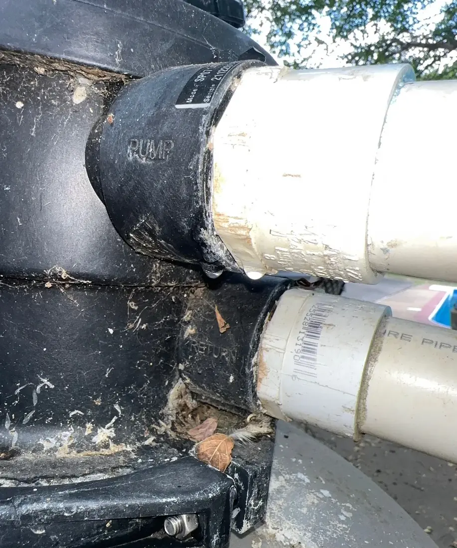 A pool filter multiport valve with PUMP and RETURN ports, showing water leaking at the pipe union