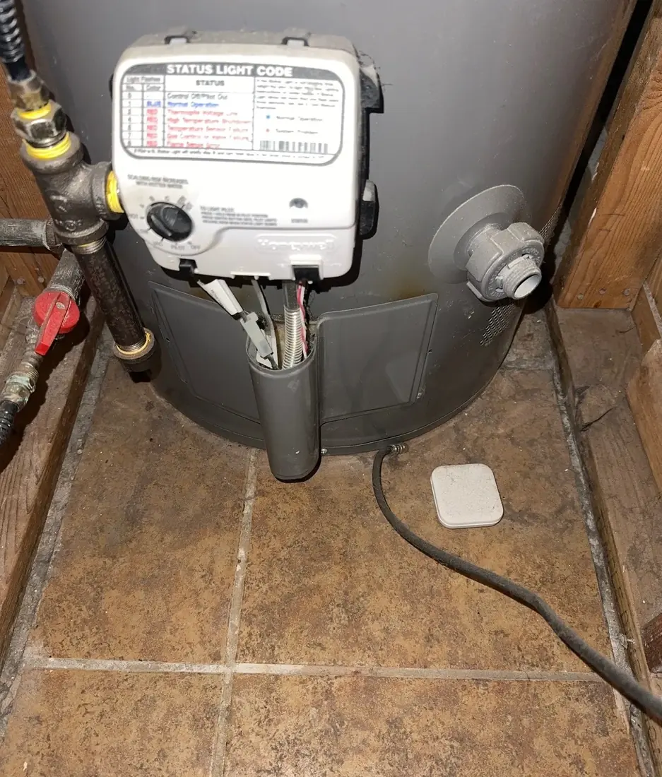 The gas control valve and status light code label at the base of a gas water heater
