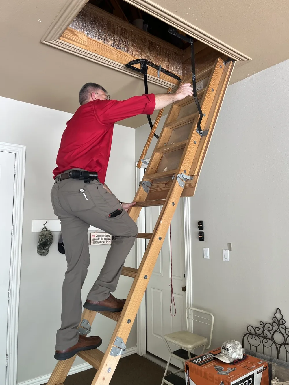 Jeff Stalnaker climbing a pull-down attic ladder during a home inspection