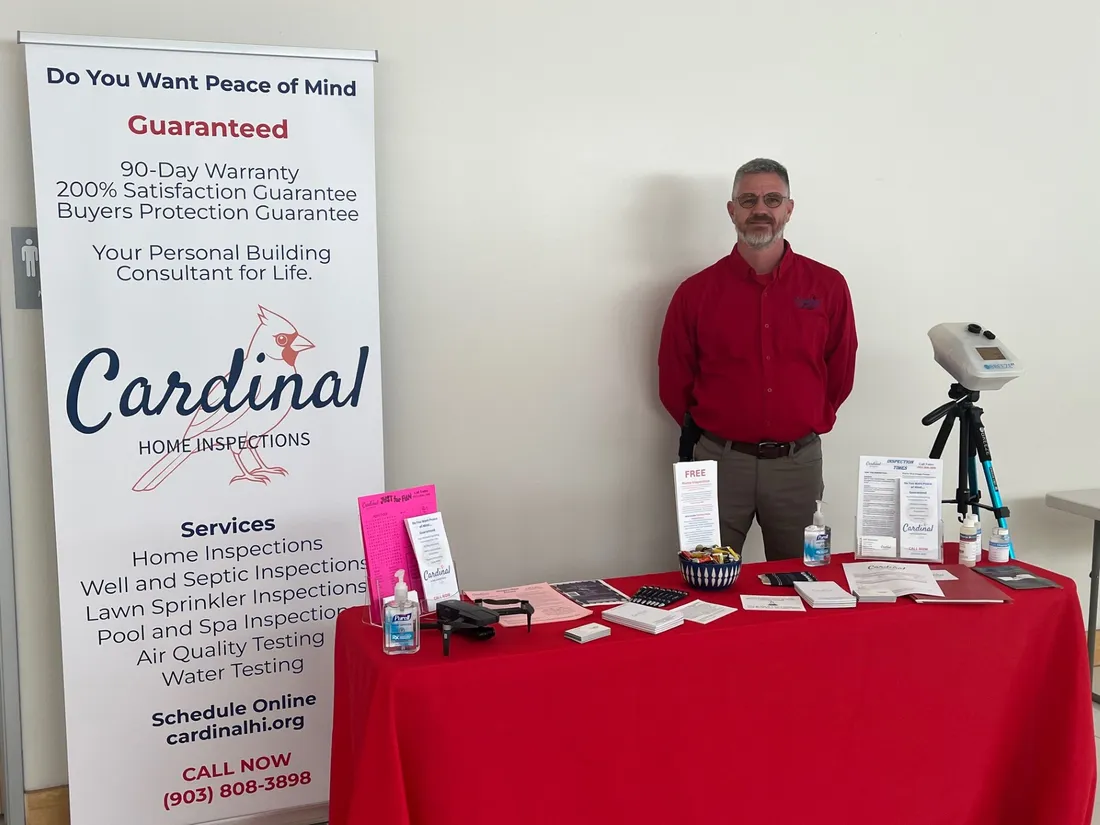 Jeff Stalnaker standing at the Cardinal Home Inspections booth at a local event, with brochures and a drone on the table