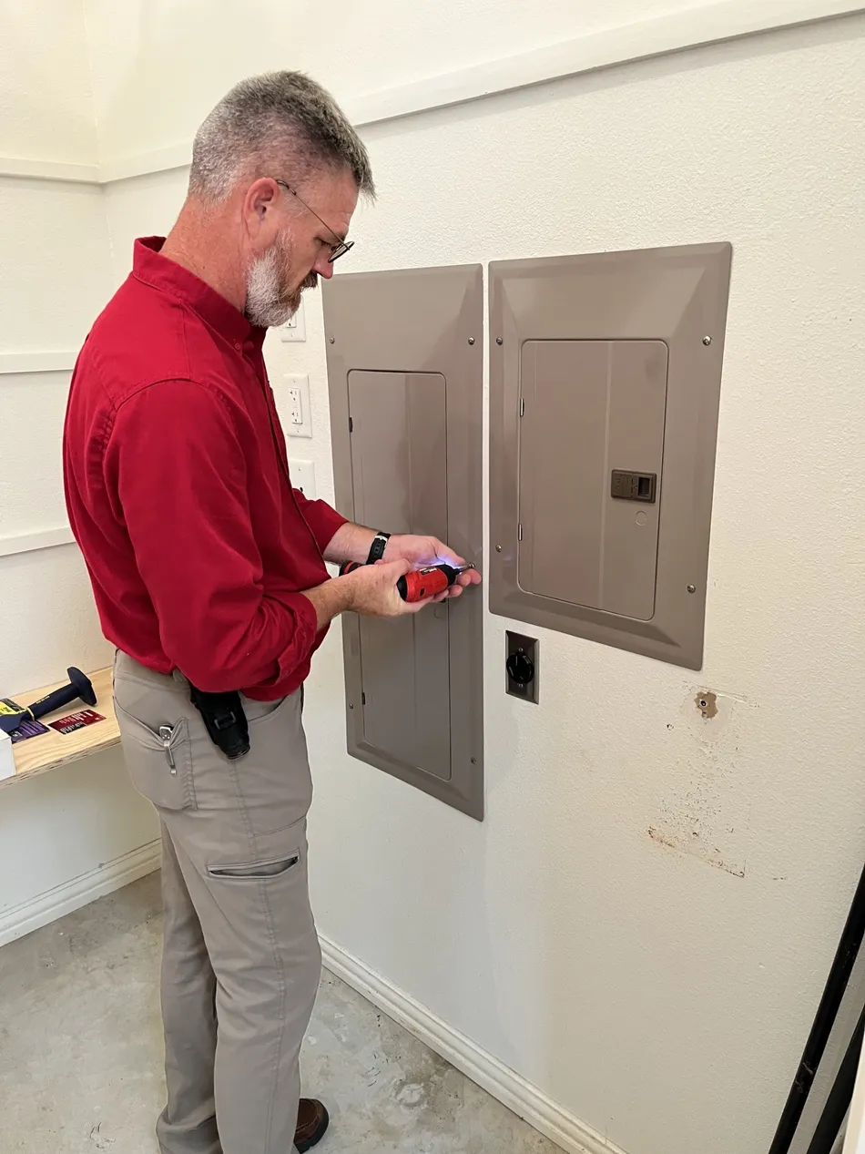 Jeff Stalnaker using a cordless driver to remove the screws from an electrical panel deadfront cover