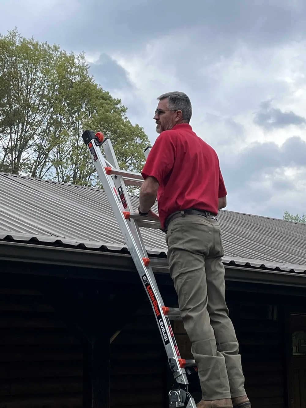 Jeff Stalnaker climbing a ladder onto a standing seam metal roof during an East Texas home inspection.