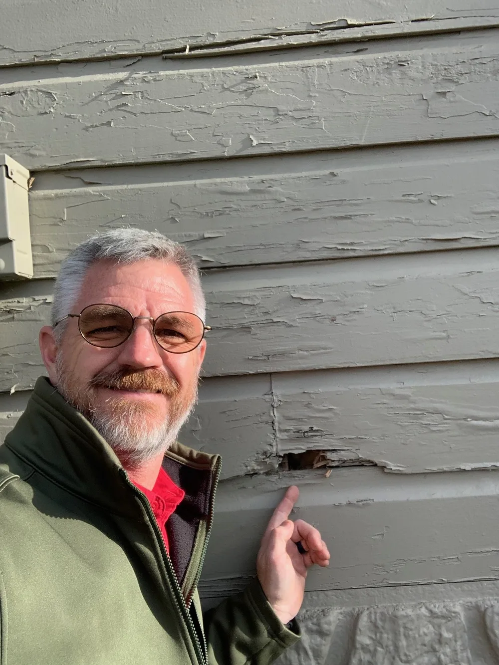 Jeff Stalnaker pointing out damaged siding on the exterior wall of a house during an inspection